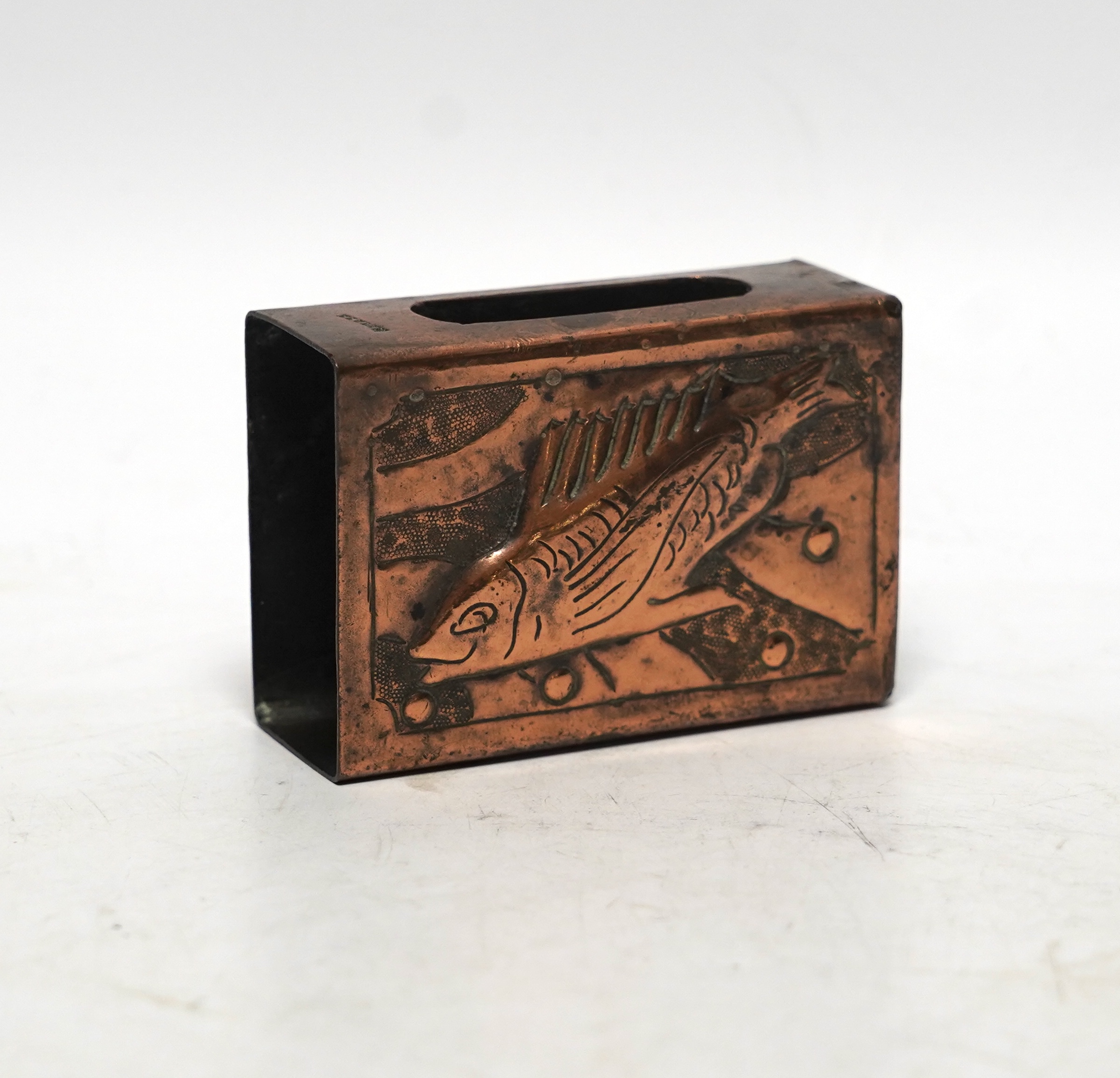 A Newlyn copper matchbox cover, decorated with a fish, 7.5cm wide